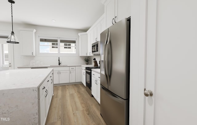 kitchen featuring white cabinets, tasteful backsplash, a sink, light wood-style flooring, and appliances with stainless steel finishes