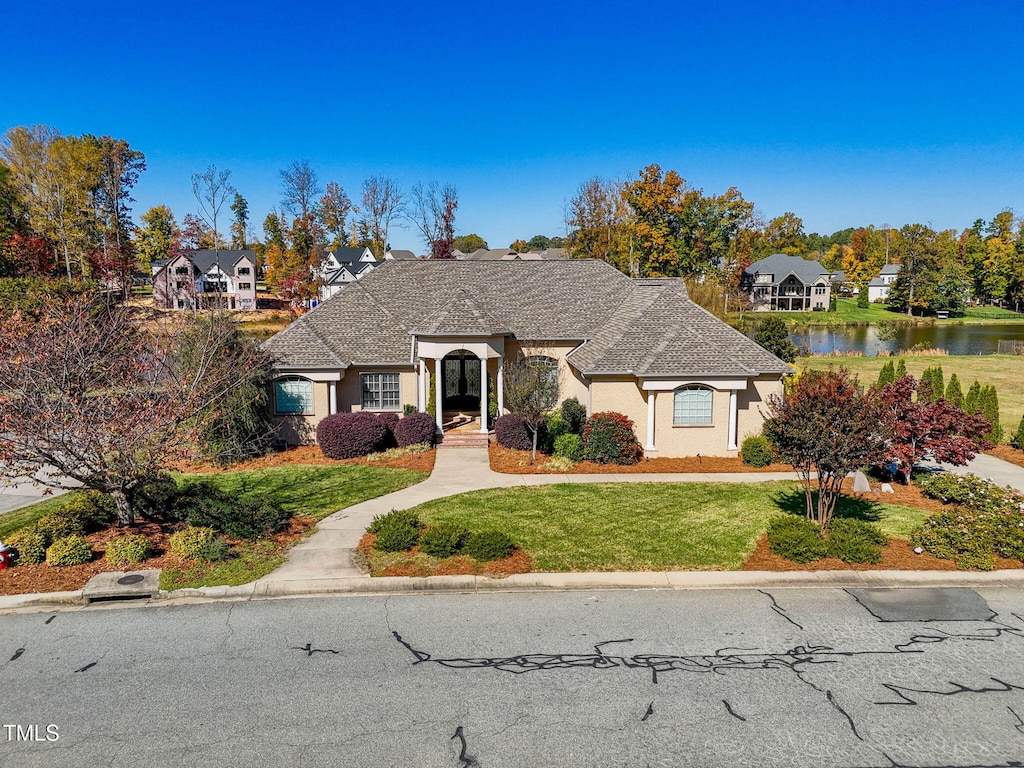 french provincial home featuring a water view and a front lawn