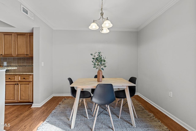 dining room with a notable chandelier, ornamental molding, and wood-type flooring