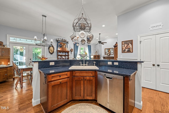 kitchen featuring sink, dishwasher, decorative light fixtures, and a center island with sink