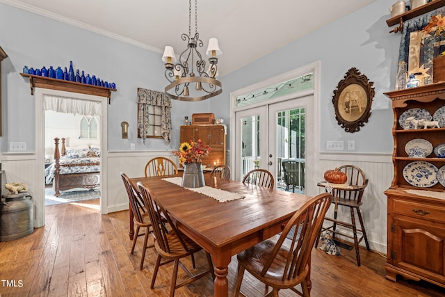 dining room featuring french doors, crown molding, a notable chandelier, and hardwood / wood-style flooring