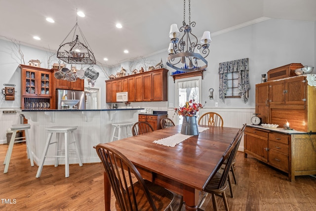 dining area with ornamental molding, a chandelier, dark wood-type flooring, and lofted ceiling