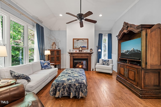 living room with light hardwood / wood-style floors, a healthy amount of sunlight, ceiling fan, and vaulted ceiling