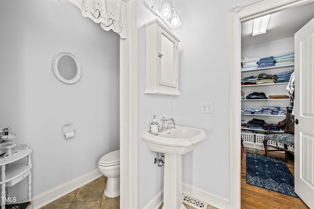 bathroom featuring toilet, sink, and wood-type flooring