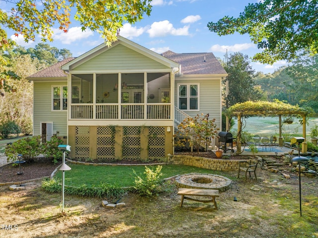 rear view of property with a patio, a fire pit, a yard, and a sunroom