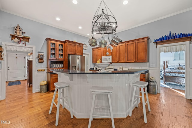 kitchen with light hardwood / wood-style flooring, crown molding, stainless steel fridge with ice dispenser, and a kitchen breakfast bar