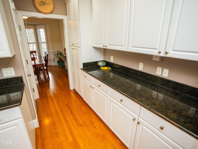 kitchen with dark stone counters, white cabinetry, and light wood-type flooring