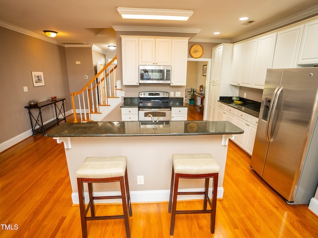 kitchen featuring light hardwood / wood-style floors, appliances with stainless steel finishes, a breakfast bar, and white cabinets