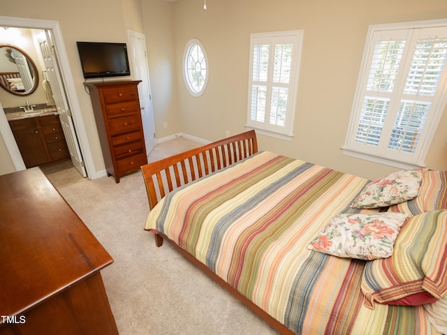 carpeted bedroom featuring multiple windows, sink, and ensuite bath
