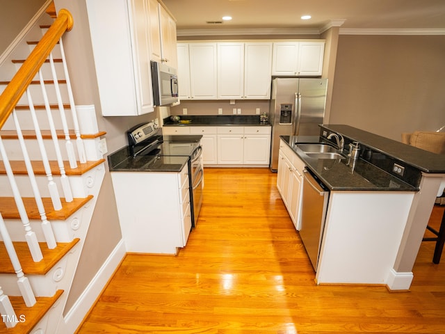 kitchen featuring light hardwood / wood-style floors, white cabinets, sink, ornamental molding, and appliances with stainless steel finishes