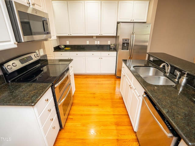 kitchen with appliances with stainless steel finishes, sink, light hardwood / wood-style floors, and white cabinets