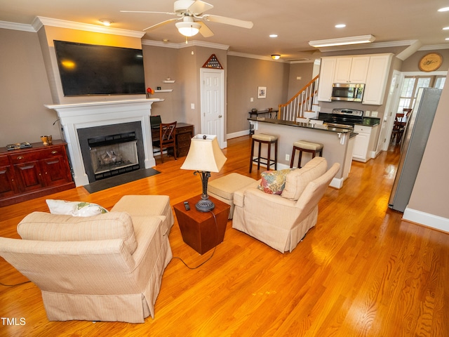 living room with ceiling fan, light wood-type flooring, and ornamental molding