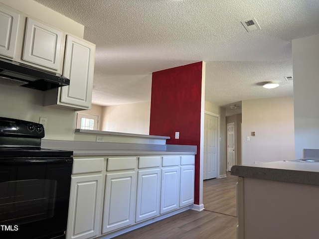 kitchen featuring a textured ceiling, kitchen peninsula, white cabinets, black / electric stove, and light hardwood / wood-style flooring