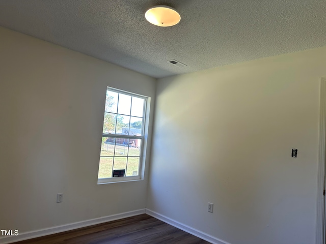 spare room with a textured ceiling and dark wood-type flooring