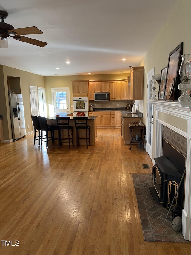 interior space with ceiling fan, a wood stove, and light hardwood / wood-style flooring