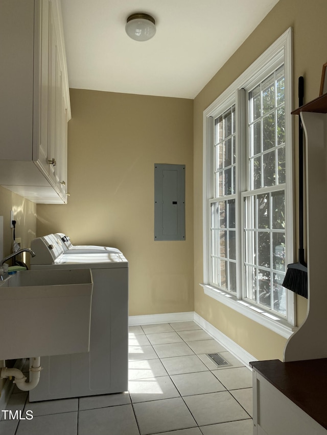 washroom with cabinets, electric panel, light tile patterned flooring, washing machine and dryer, and sink