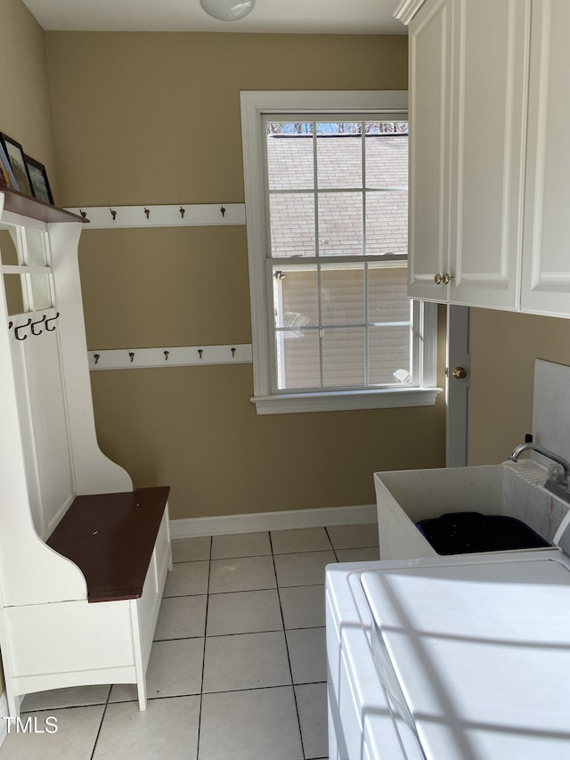 laundry area featuring sink, cabinets, and light tile patterned flooring