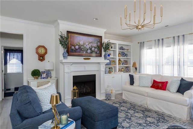 living room featuring built in shelves, an inviting chandelier, light hardwood / wood-style floors, and ornamental molding