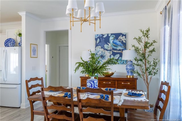 dining area with crown molding, light wood-type flooring, and a notable chandelier