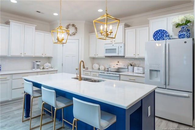 kitchen with white cabinetry, sink, decorative light fixtures, white appliances, and a center island with sink