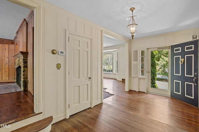 entrance foyer with wooden walls, an inviting chandelier, and dark hardwood / wood-style flooring