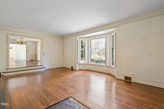 spare room with ornamental molding, hardwood / wood-style flooring, and an inviting chandelier