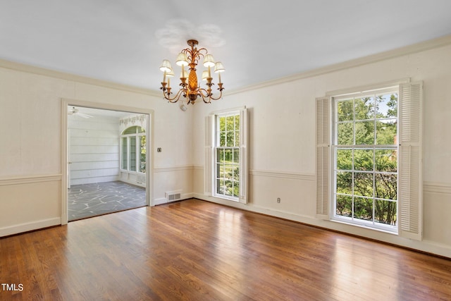 spare room featuring an inviting chandelier, crown molding, and wood-type flooring