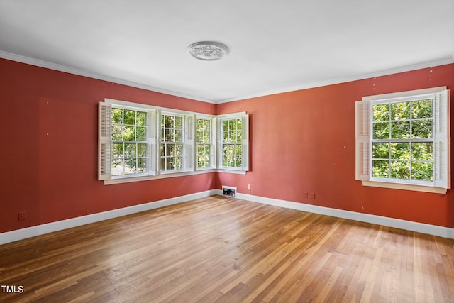 empty room featuring ornamental molding, hardwood / wood-style floors, and plenty of natural light