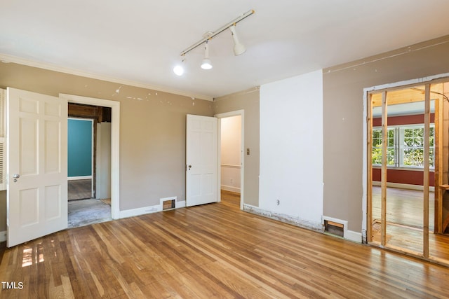 unfurnished bedroom with wood-type flooring and rail lighting