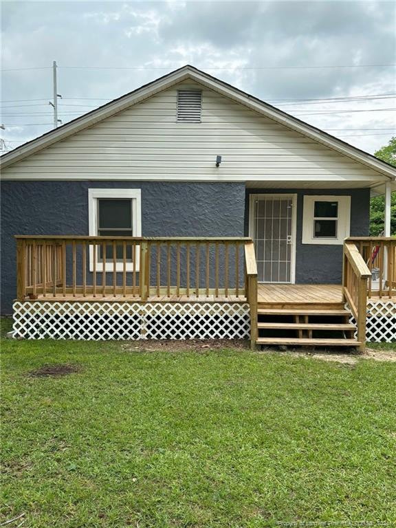 back of property featuring a deck and a yard