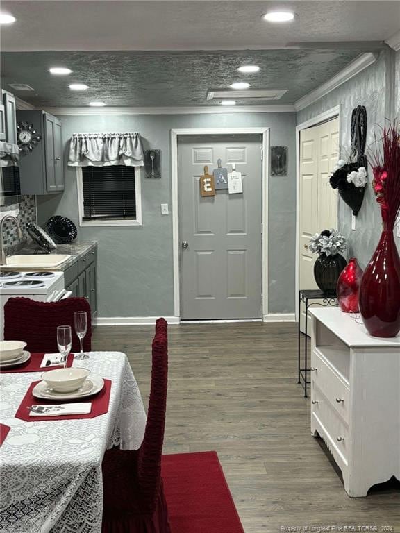 dining space featuring a textured ceiling, ornamental molding, sink, and hardwood / wood-style floors