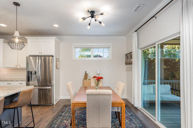 dining room featuring dark wood-type flooring, a healthy amount of sunlight, and ornamental molding