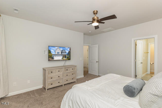 carpeted bedroom with ceiling fan and ensuite bathroom