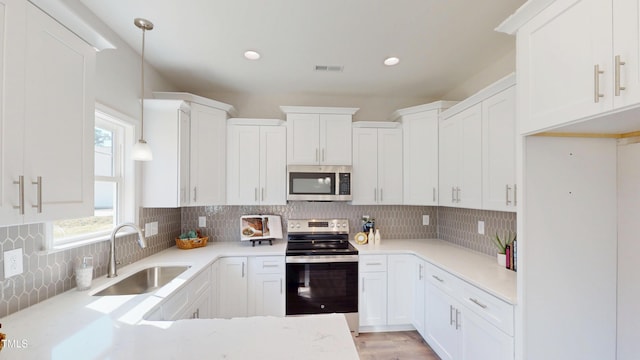 kitchen with visible vents, a sink, light countertops, appliances with stainless steel finishes, and backsplash