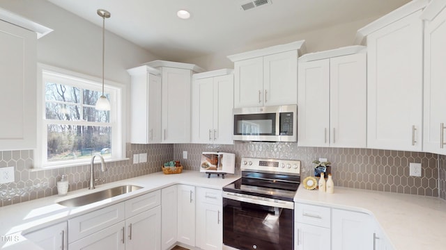 kitchen with a sink, visible vents, white cabinetry, and stainless steel appliances