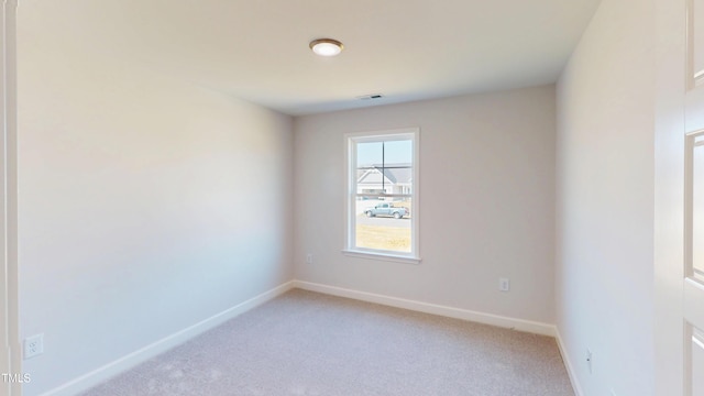 empty room with visible vents, baseboards, and light colored carpet