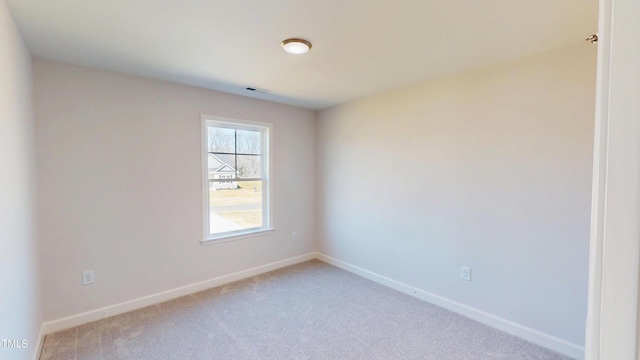 carpeted spare room featuring visible vents and baseboards