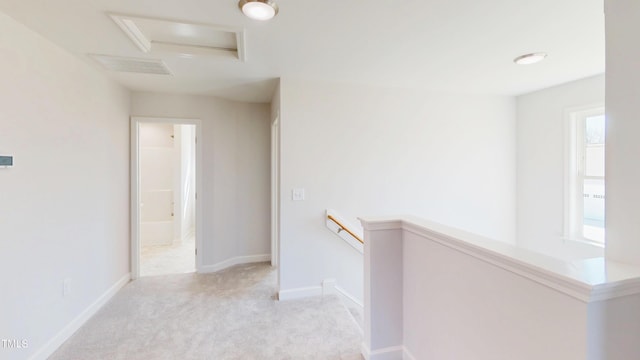 hallway featuring visible vents, light carpet, attic access, an upstairs landing, and baseboards