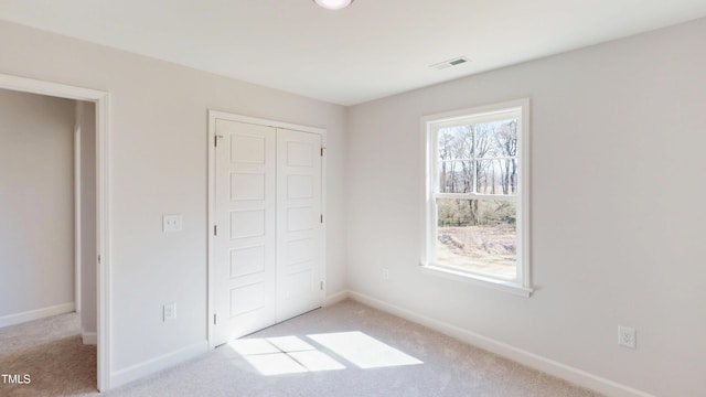 unfurnished bedroom with a closet, visible vents, baseboards, and carpet
