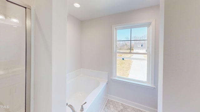 full bath with baseboards, a garden tub, and a stall shower