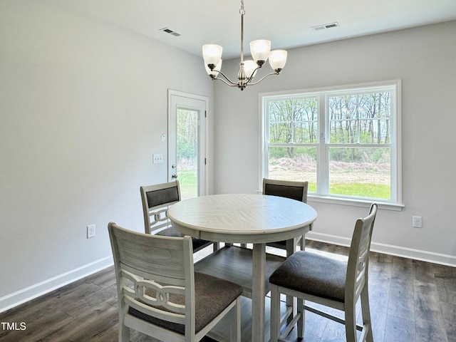 dining room featuring dark wood-type flooring, visible vents, a notable chandelier, and a healthy amount of sunlight