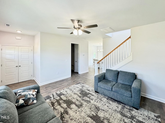 living room with stairway, visible vents, ceiling fan with notable chandelier, and baseboards
