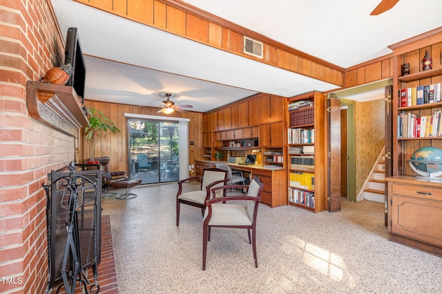 interior space with ornamental molding, wood walls, a fireplace, and ceiling fan