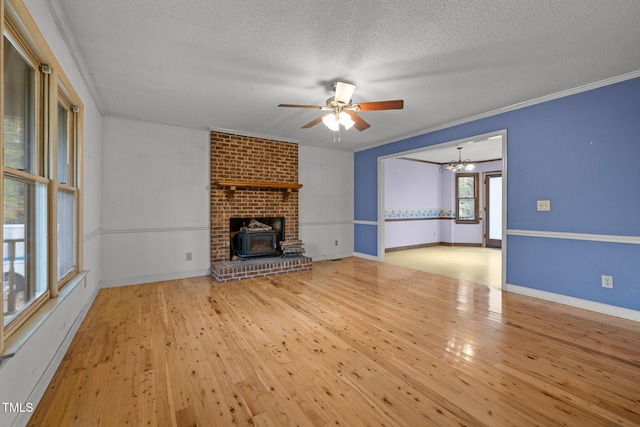 unfurnished living room with ceiling fan with notable chandelier, a textured ceiling, light wood-type flooring, and crown molding