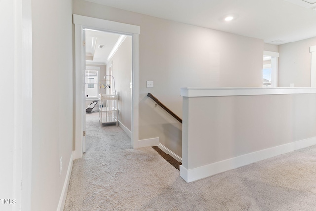 hallway with crown molding and light colored carpet