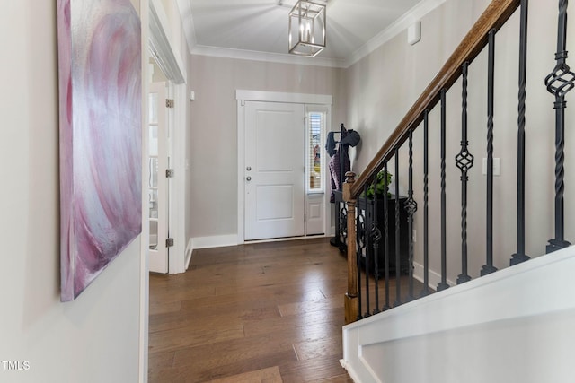 foyer entrance featuring dark wood-type flooring, a chandelier, and crown molding