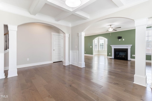 unfurnished living room featuring ornate columns, ceiling fan, dark hardwood / wood-style floors, crown molding, and beam ceiling