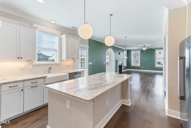 kitchen with appliances with stainless steel finishes, a center island, decorative light fixtures, white cabinetry, and tasteful backsplash