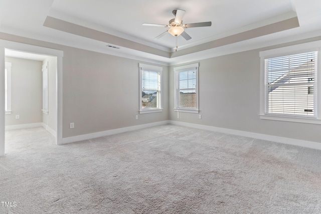 unfurnished room with ceiling fan, a wealth of natural light, crown molding, and a raised ceiling