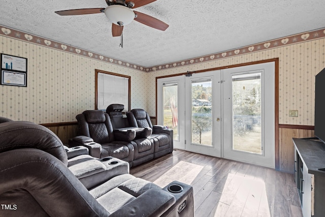 living room featuring french doors, a textured ceiling, light wood-type flooring, and ceiling fan